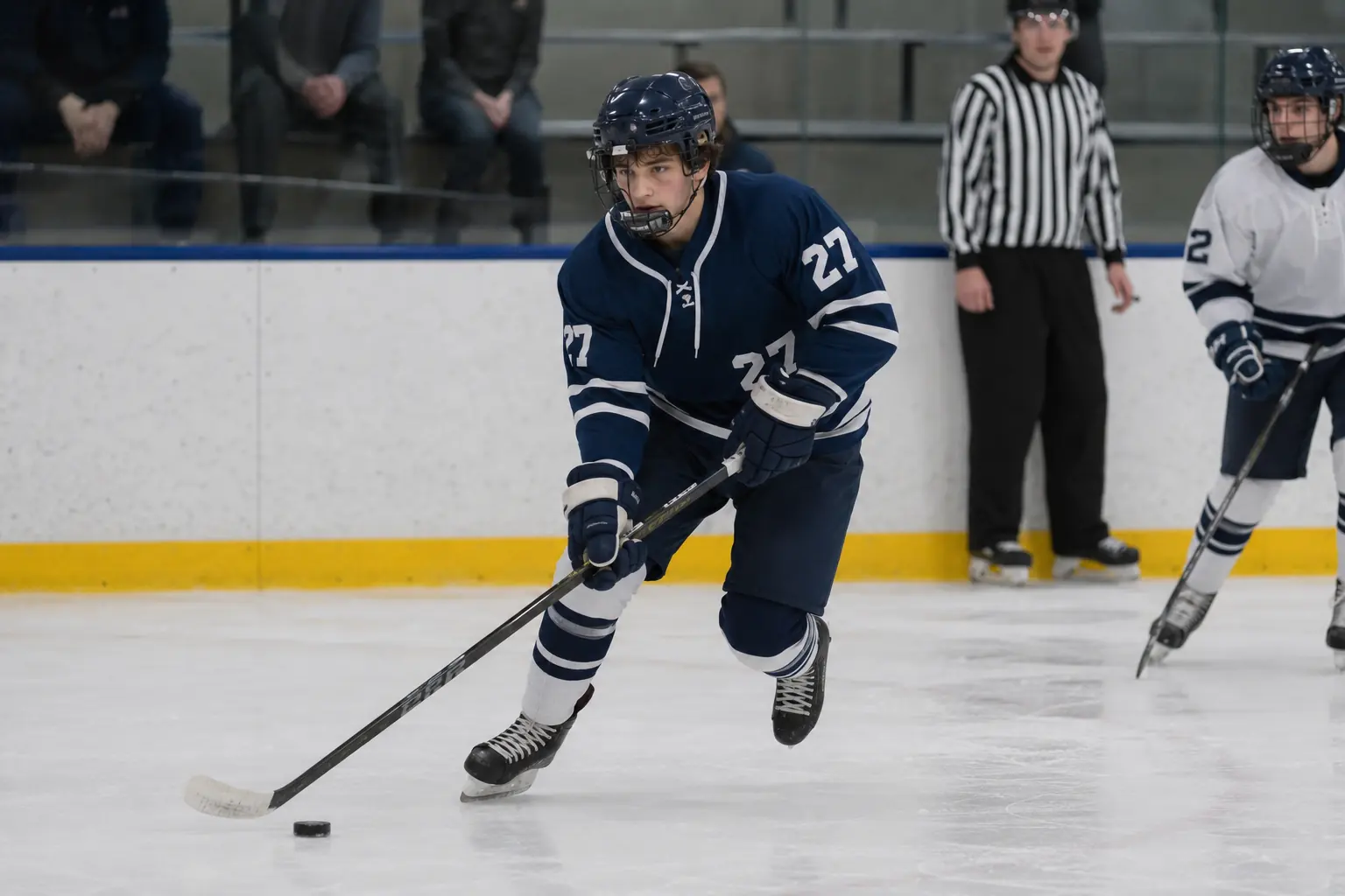 Winter hockey, first varsity shift. Illustrative photo of a high school hockey player in a navy number 27 sweater, about fifteen years old, carrying the puck across the blue line.